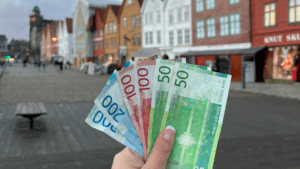 Foto segurando coroas norueguesas na frente de Bryggen. Arquivo pessoal