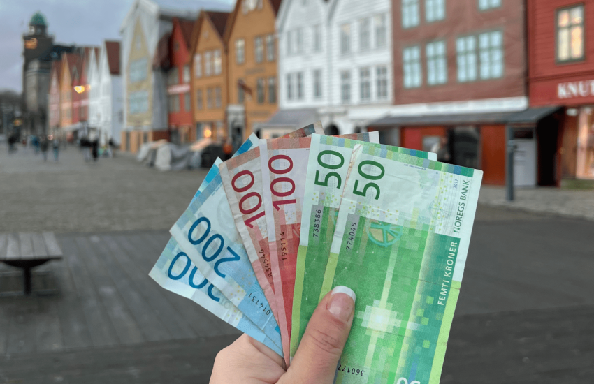 Foto segurando coroas norueguesas na frente de Bryggen. Arquivo pessoal